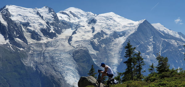 People sitting on snowcapped mountain against sky