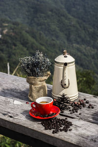 Red tea cup on table against trees