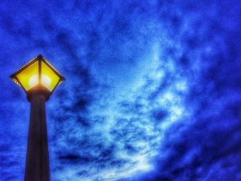 Low angle view of illuminated lamp against blue sky