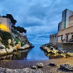 Buildings by sea against sky
