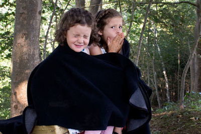 Girl making face while standing in forest