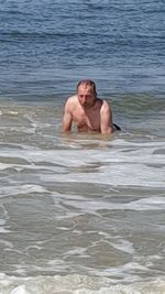 Full length of shirtless man swimming in sea