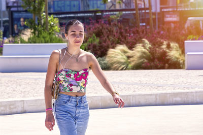 Portrait of young woman standing against wall