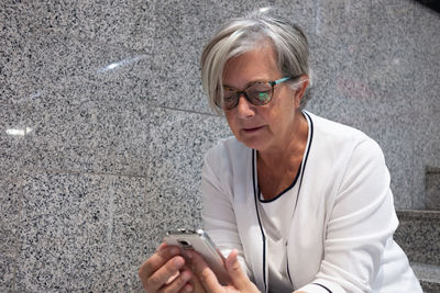 Senior woman using phone while sitting on steps