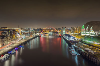 Boats moored at canal amidst illuminated city at night