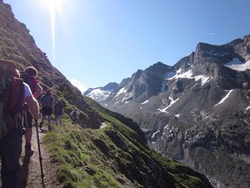 Rear view of people hiking on mountain against sky