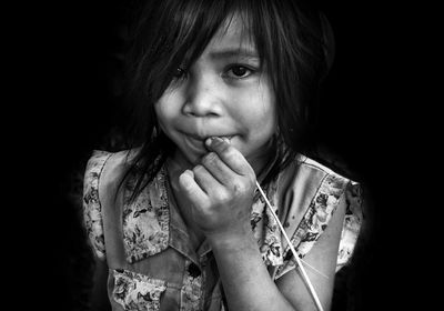 Close-up portrait of girl smiling against black background