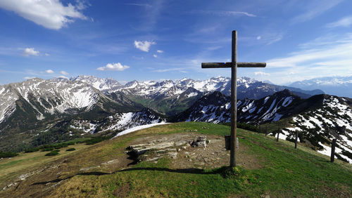 Cross on snow covered mountains against sky