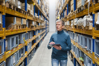 Businessman taking inventory holding tablet pc in warehouse