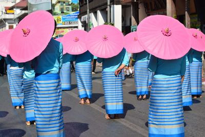 Rear view of parade of women in traditional clothing with umbrella