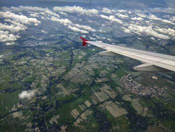 Airplane flying over agricultural landscape against sky