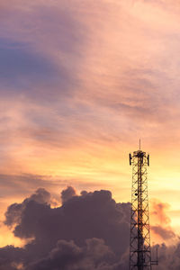 Low angle view of electricity pylon against sky during sunset