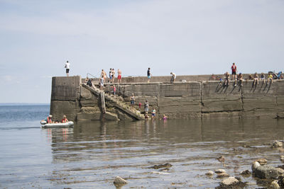 People on boats in sea against sky