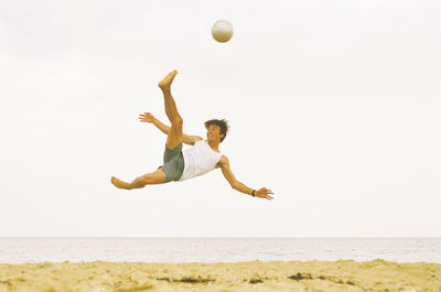 Low angle view of man playing ball on beach