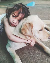 Close-up portrait of girl embracing dog on floor