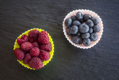 Close-up of raspberries and blueberries in cupcake holder on table
