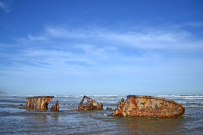 Shipwreck at beach against sky