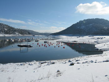 Scenic view of river by snow covered mountain against clear blue sky