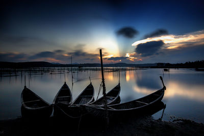 Boats moored in lake against sky during sunset