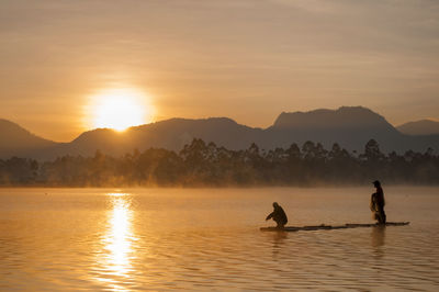 Silhouette people on mountain against sky during sunset