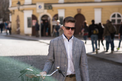 Young man wearing sunglasses standing on street in city