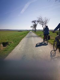 Rear view of man riding bicycle on road against sky