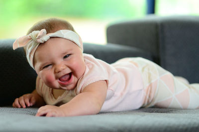 Portrait of cute baby girl lying on bed at home