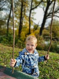 Portrait of boy holding plants against trees