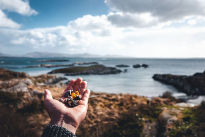 Midsection of person holding sea against sky