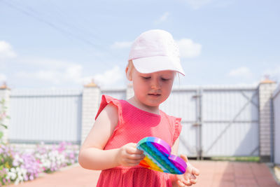 Cute caucasian fair hair girl in pink dress is playing and showing funny trendy silicone antistress 