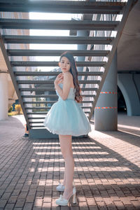 Full length of young woman standing on footpath