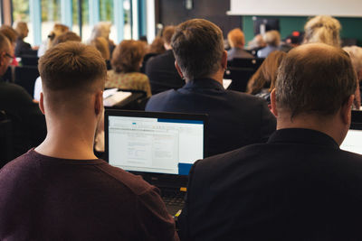 Rear view of people sitting on laptop