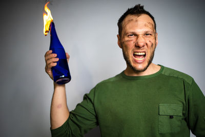 Portrait of young man holding sparkler against wall