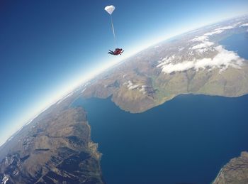 Person sky diving over mountains against