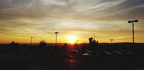 Silhouette cars on road against sky during sunset