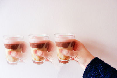 Close-up of hand holding drink against white background