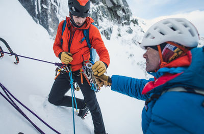 Two male alpine ice climbers sort and exchange ice and rock gear