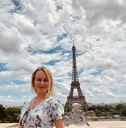 Portrait of woman with tower against cloudy sky