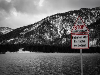 Information sign by lake against sky