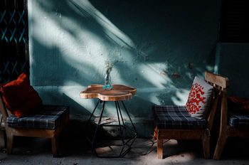 Empty chairs and table against wall at sidewalk cafe