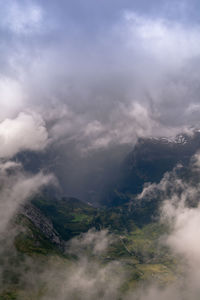 Scenic view of mountains in foggy weather against cloudy sky