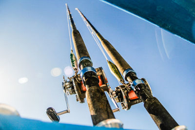 Low angle view of fishing poles against sky