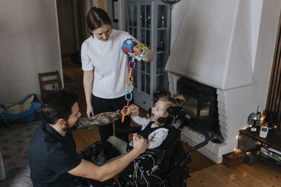 Parents playing with smiling disabled child in wheelchair