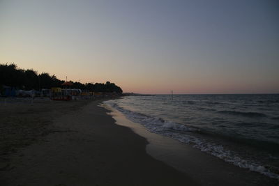 Scenic view of beach against clear sky during sunset