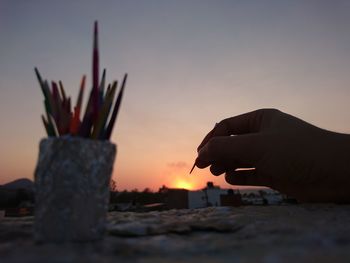 Cropped hand holding toothpick against sky