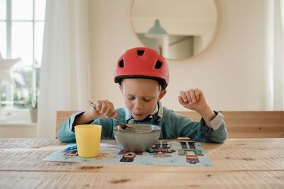 Young boy eating dinner with his bike helmet on eager to go outside