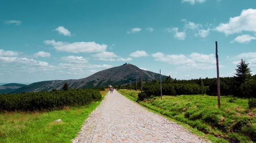 Road amidst field against sky