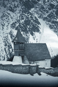 Traditional building by snowcapped mountain against sky