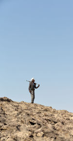 Man standing on rock against clear sky