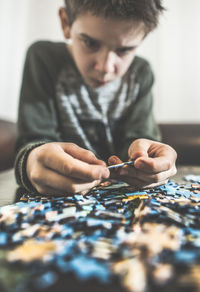 Boy playing with jigsaw puzzle on table at home